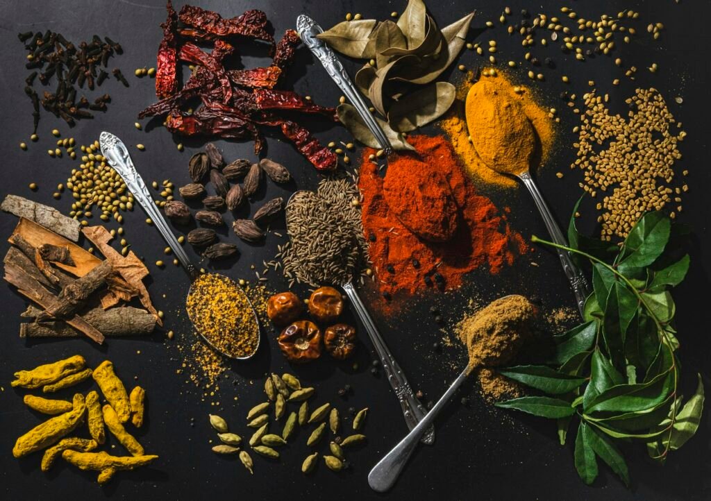 Whole and ground spices spread across a dark table